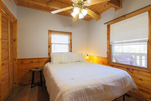 A bedroom with a wooden ceiling, a bed with white bedding, a nightstand, and a window with blinds. - Almost Heaven - Minutes to the Parkway!! (Pigeon Forge)