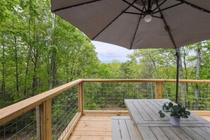 Une terrasse en bois avec une rambarde en métal, une table et un pot de fleurs.