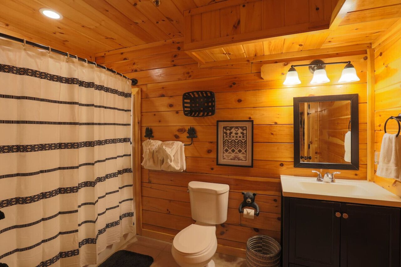 Ein Badezimmer einer Holzhütte mit Toilette, Waschbecken und Spiegel.