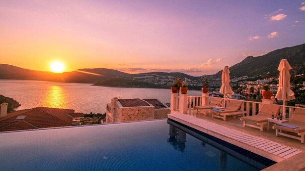Ein Infinity-Pool mit Blick auf den Sonnenuntergang über dem Meer und den Bergen.