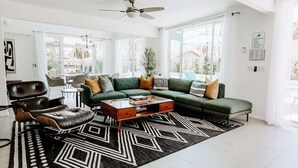 Una sala de estar moderna con un sofá verde, un sillón de cuero y una mesa de centro.