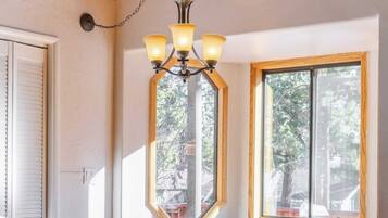 A rustic wooden dining table with benches, a chandelier, and large windows.