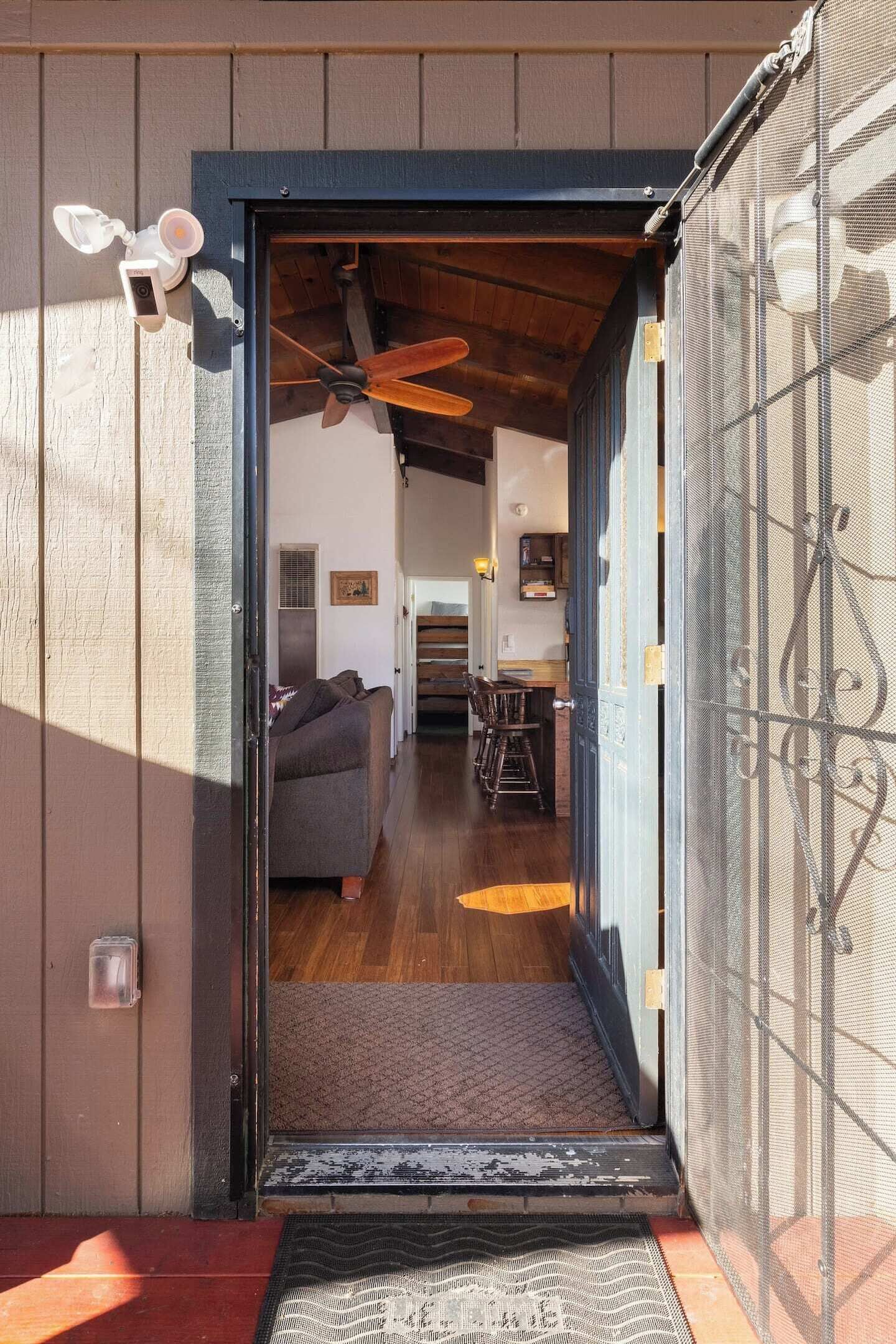 A doorway leading into a room with a ceiling fan, a sofa, and a dining area with chairs.