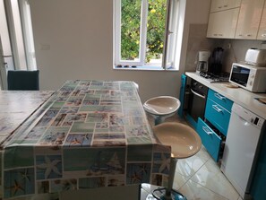 Una cucina con piastrelle a parete, una finestra vista sul verde, un forno a microonde, un fornello e una lavastoviglie.