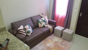 A living room with a sofa, two pillows, a throw blanket, and a small ottoman. - MY RELAX- VAMAR LUXURY CONDO (Puerto Plata)