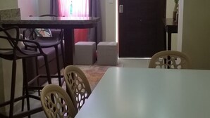 A dining area with a table and chairs, a kitchen area with a counter, and a door leading to another room. - MY RELAX- VAMAR LUXURY CONDO (Puerto Plata)
