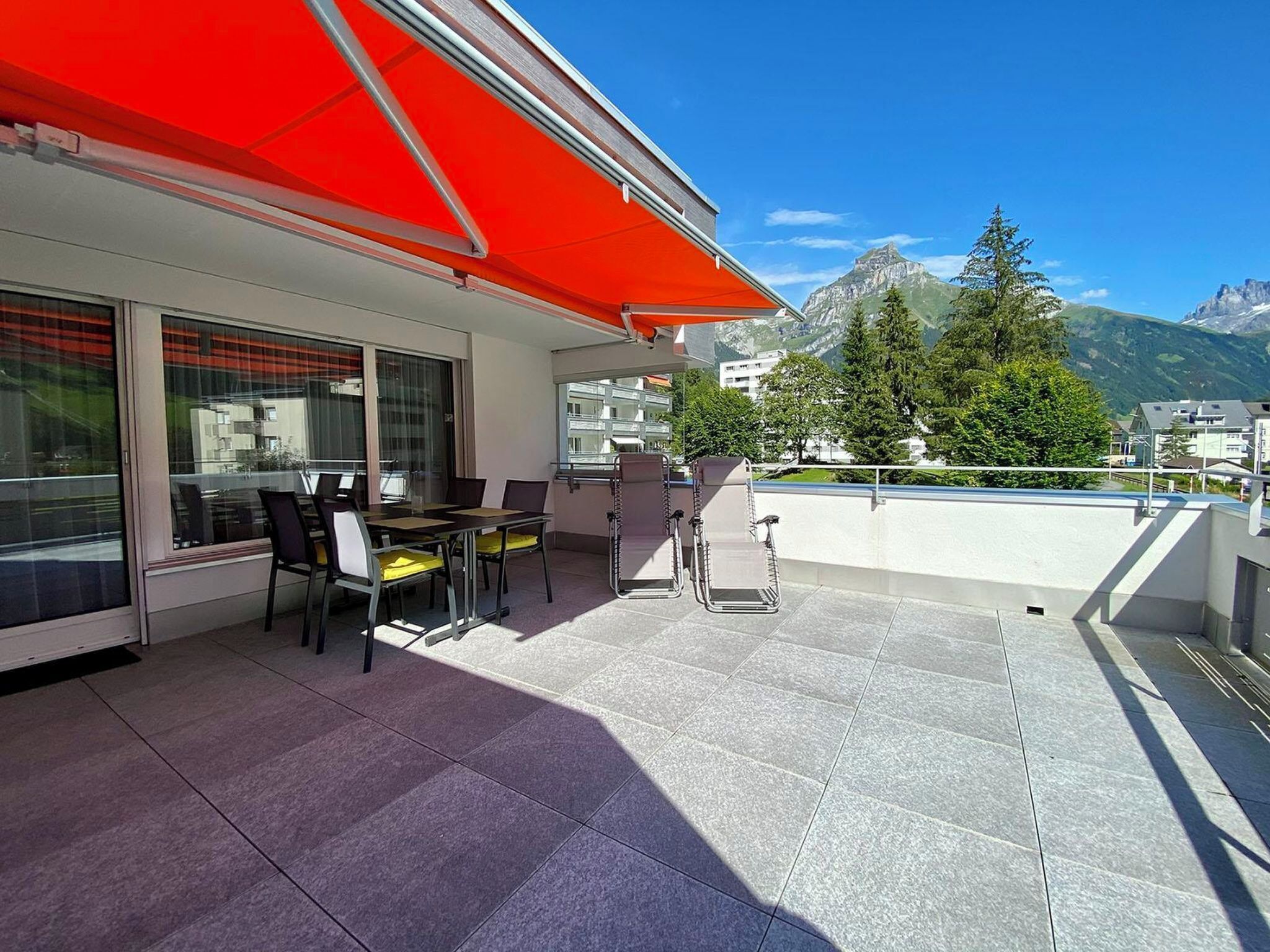 Un balcon avec un auvent rouge, des sièges pour l’extérieur et une vue sur les montagnes.