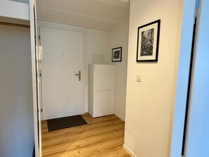 A hallway with a wooden floor, a white door, a white cabinet, and a framed picture on the wall.
