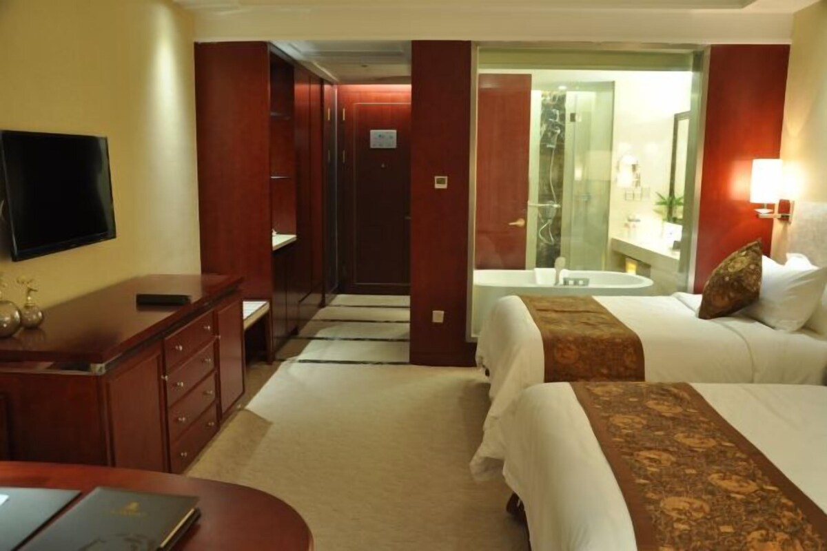 A hotel room with a bed, bedside table, and a TV on the wall.