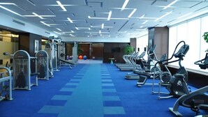 Une salle de sport équipée de matériel d’exercice, dotée d’un tapis bleu et d’un plafond au design moderne.