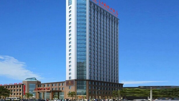Un grand hôtel à la façade moderne en verre, surmonté d’une enseigne rouge.