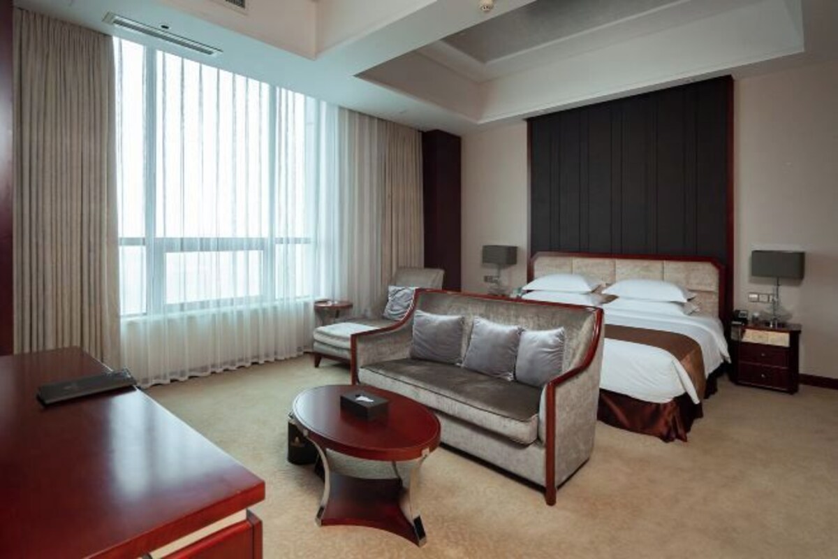 Une chambre d’hôtel avec un lit, un canapé, un bureau et une fenêtre.