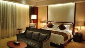 Une chambre d’hôtel avec un grand lit, un canapé, une table basse et un bureau avec une lampe.