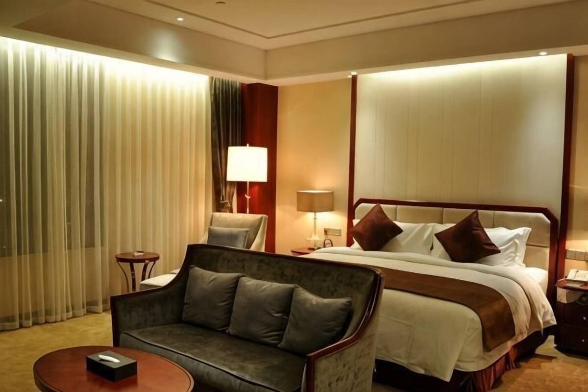 Habitació d'hotel amb un llit, un sofà, una làmpada i un televisor sobre una taula.