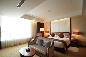 A hotel room with a bed, a sofa, a small table, and a nightstand with lamps.