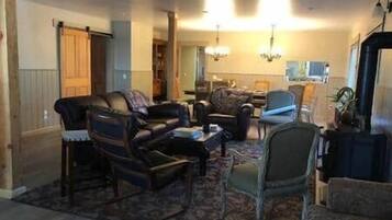 Una sala de estar con un sofá, sillones, una mesa de centro y una alfombra. Un candelabro cuelga del techo.