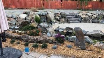 Um jardim com um caminho de pedra, pedras e um pequeno lago.