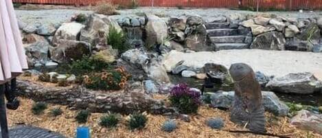 A garden with a stone pathway, rocks, and a small pond.