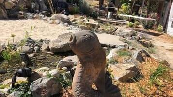 Un jardín con una gran escultura de piedra, rocas y plantas.