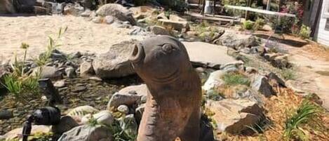 Un jardin agrémenté d’une grande sculpture en pierre, de rochers et de plantes.