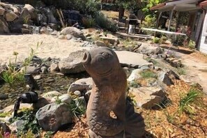A garden with a large stone sculpture, rocks, and plants.