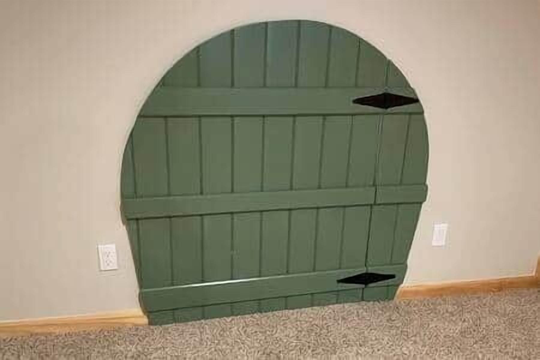 Quarto com cabeceira verde em frente a uma parede lisa.