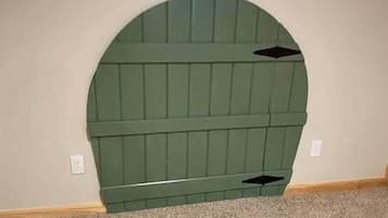 Quarto com cabeceira verde em frente a uma parede lisa.
