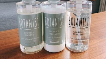 Drei Flaschen Botanist-Produkte auf einem Holztisch.