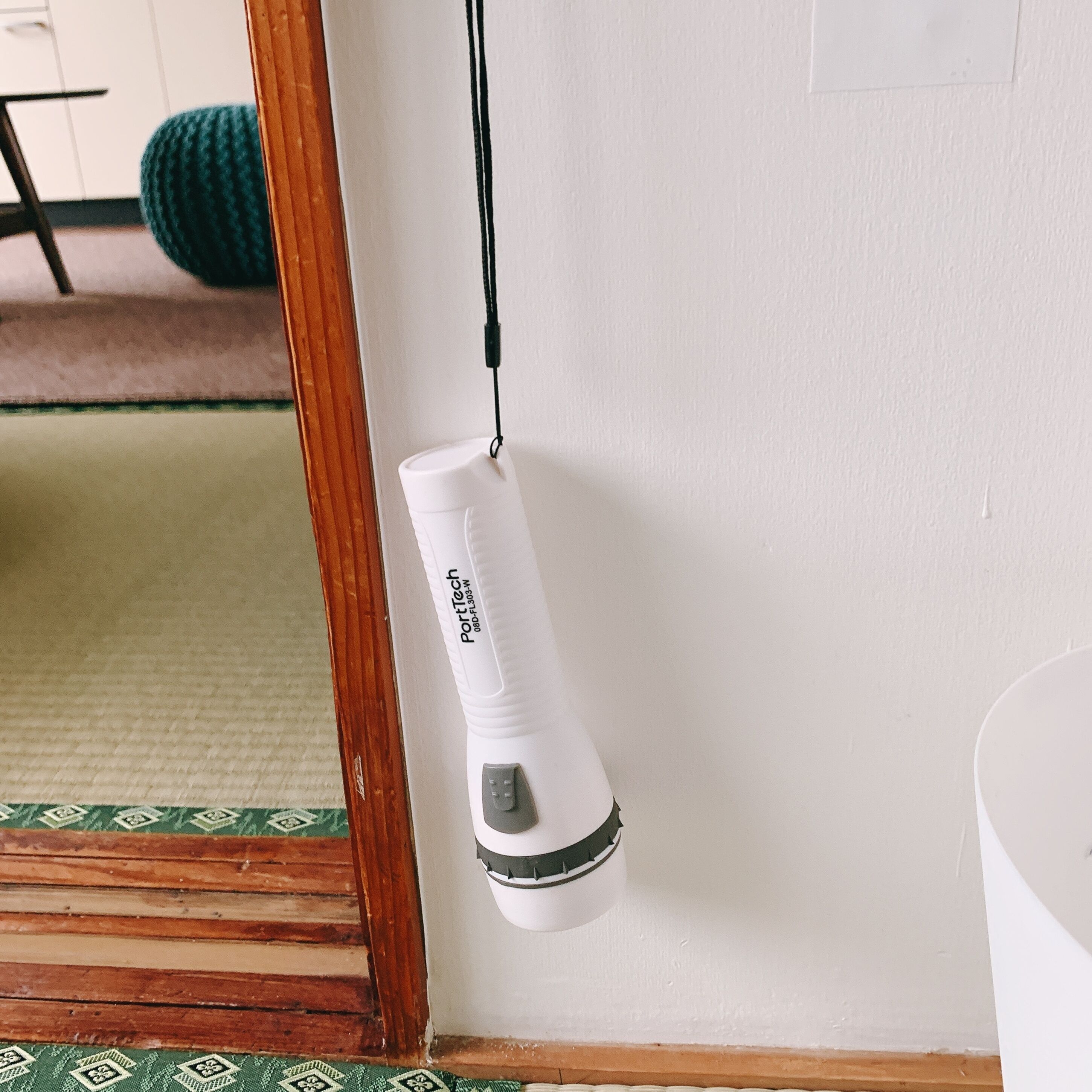 A white portable air purifier hanging on a wall near a mirror.