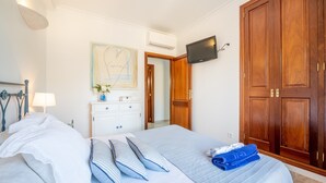 A bedroom with a bed, a dresser, a TV, and a wardrobe. - Cozy Apartment 3 Minutes from the Beach with Air Conditioning, Terrace & Garden (Alcudia)