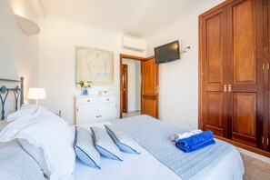 Une chambre à coucher avec un lit, une commode, un téléviseur et une armoire.