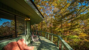 A wooden deck with a railing, benches, and a view of a forest. - Tree House in Center of Helen (Helen)