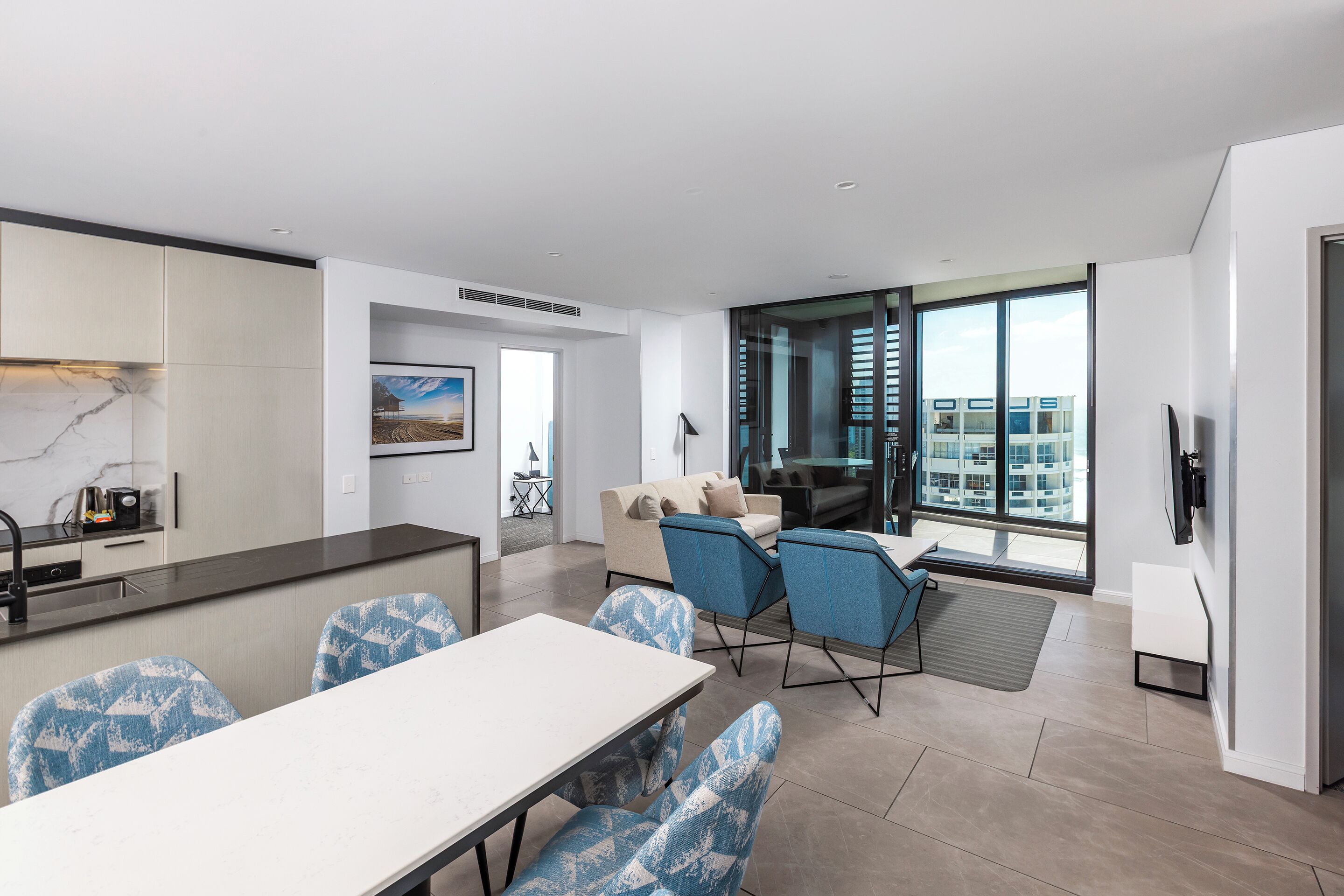 A modern apartment with a kitchen, dining area, and a large window offering a city view.