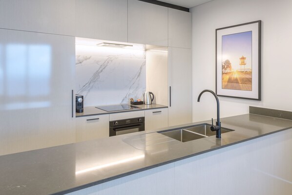 Una cocina moderna con salpicadero de mármol, electrodomésticos de acero inoxidable y un cuadro en la pared.