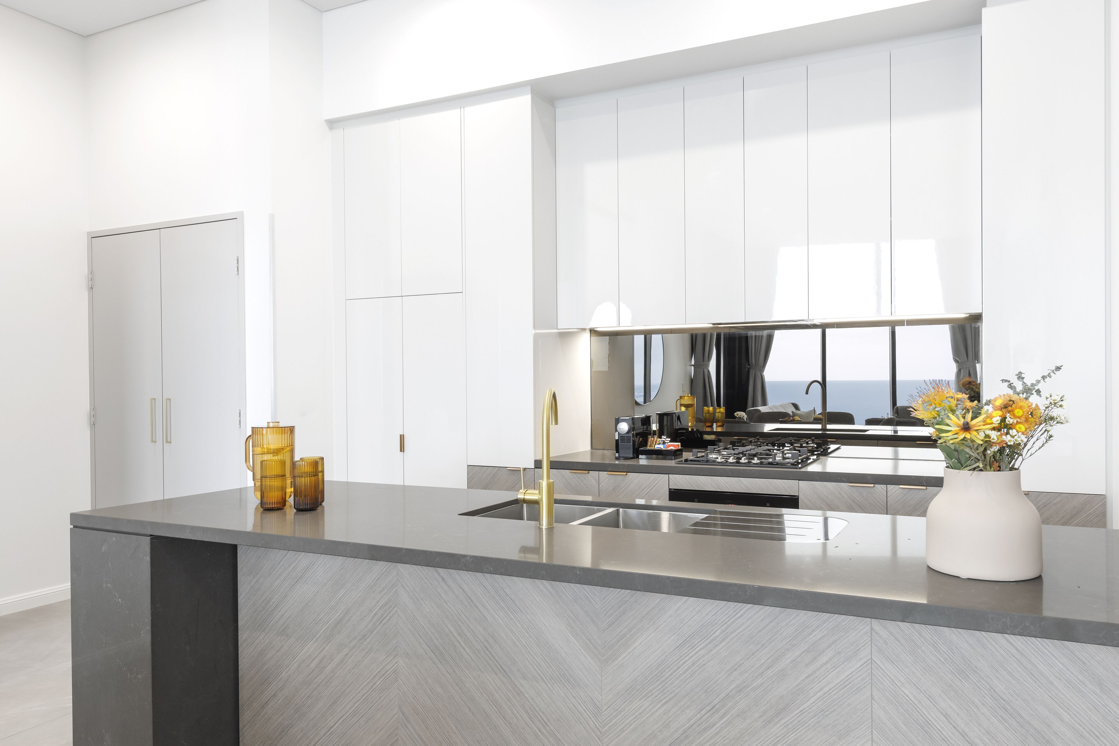 A modern kitchen with a central island, stainless steel appliances, and a view of the ocean.