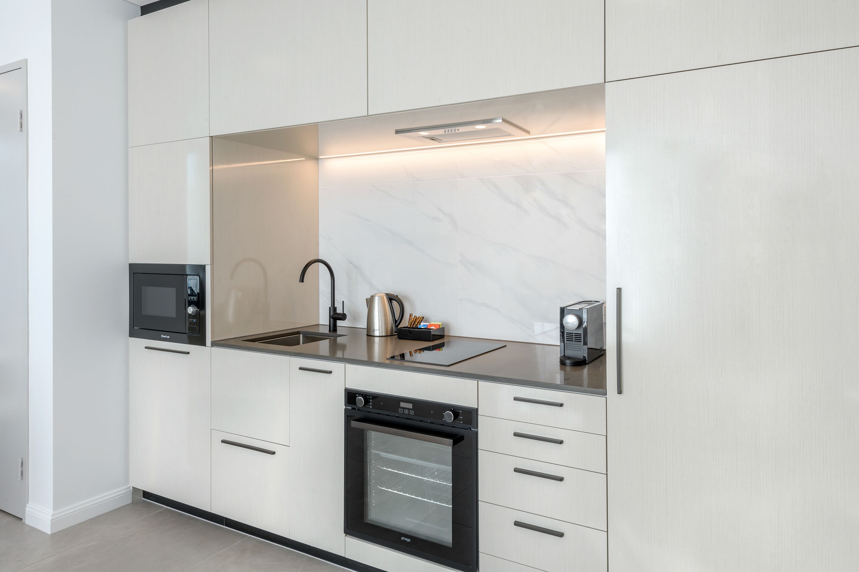 A modern kitchen with a built-in oven, microwave, and coffee maker.