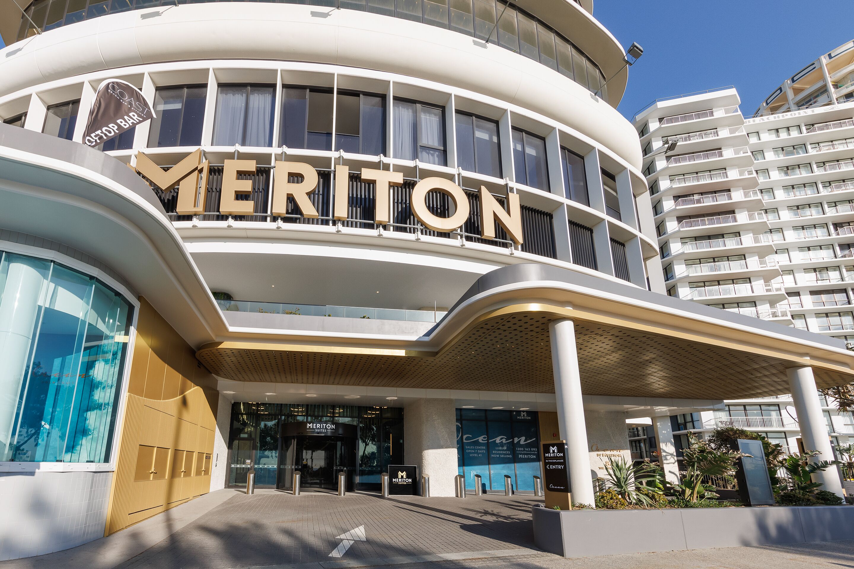 Un hotel moderno con un'imponente insegna 'MERITON', ampie finestre e un'area d'ingresso coperta.