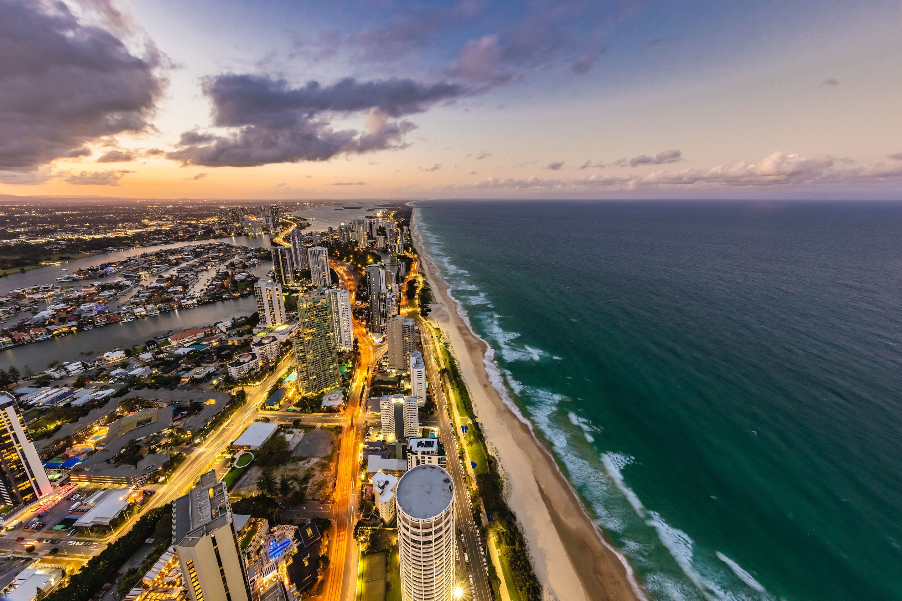 A coastal cityscape with high-rise buildings, a beach, and a marina.