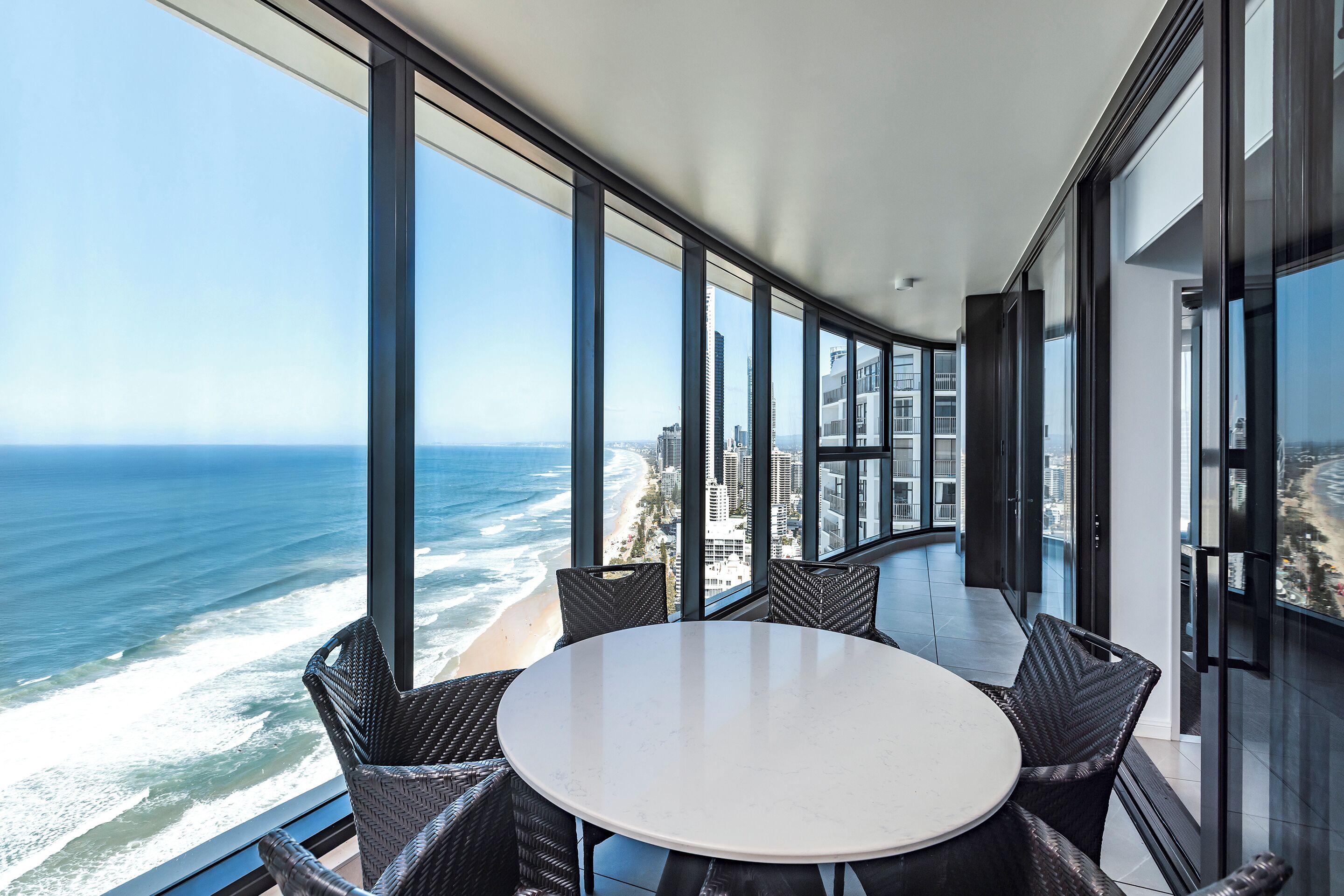 A high-rise room with a large window overlooking a beach and ocean.