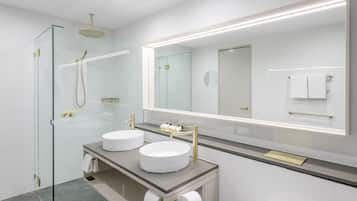 Un baño moderno con dos lavamanos, cabina de ducha de cristal y un espejo grande.