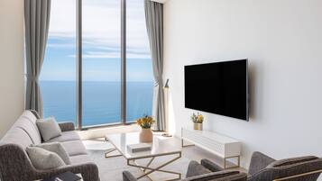 A modern living room with a large window, a flat-screen TV, and a sofa set.
