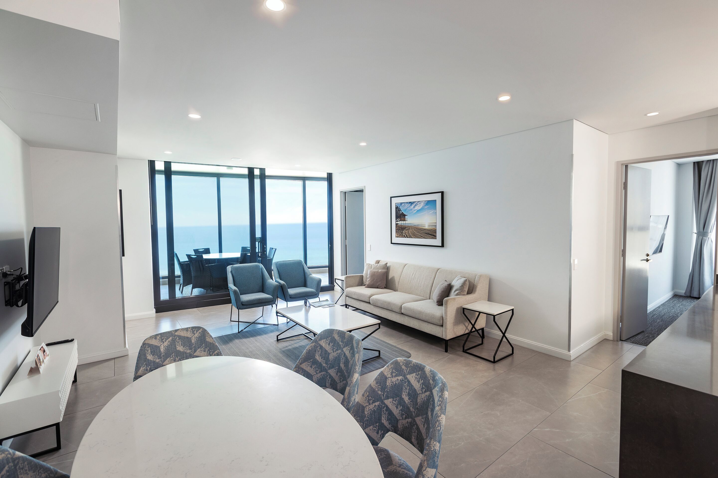 Una sala de estar moderna con un ventanal grande, un sofá, una mesa de centro y un comedor.