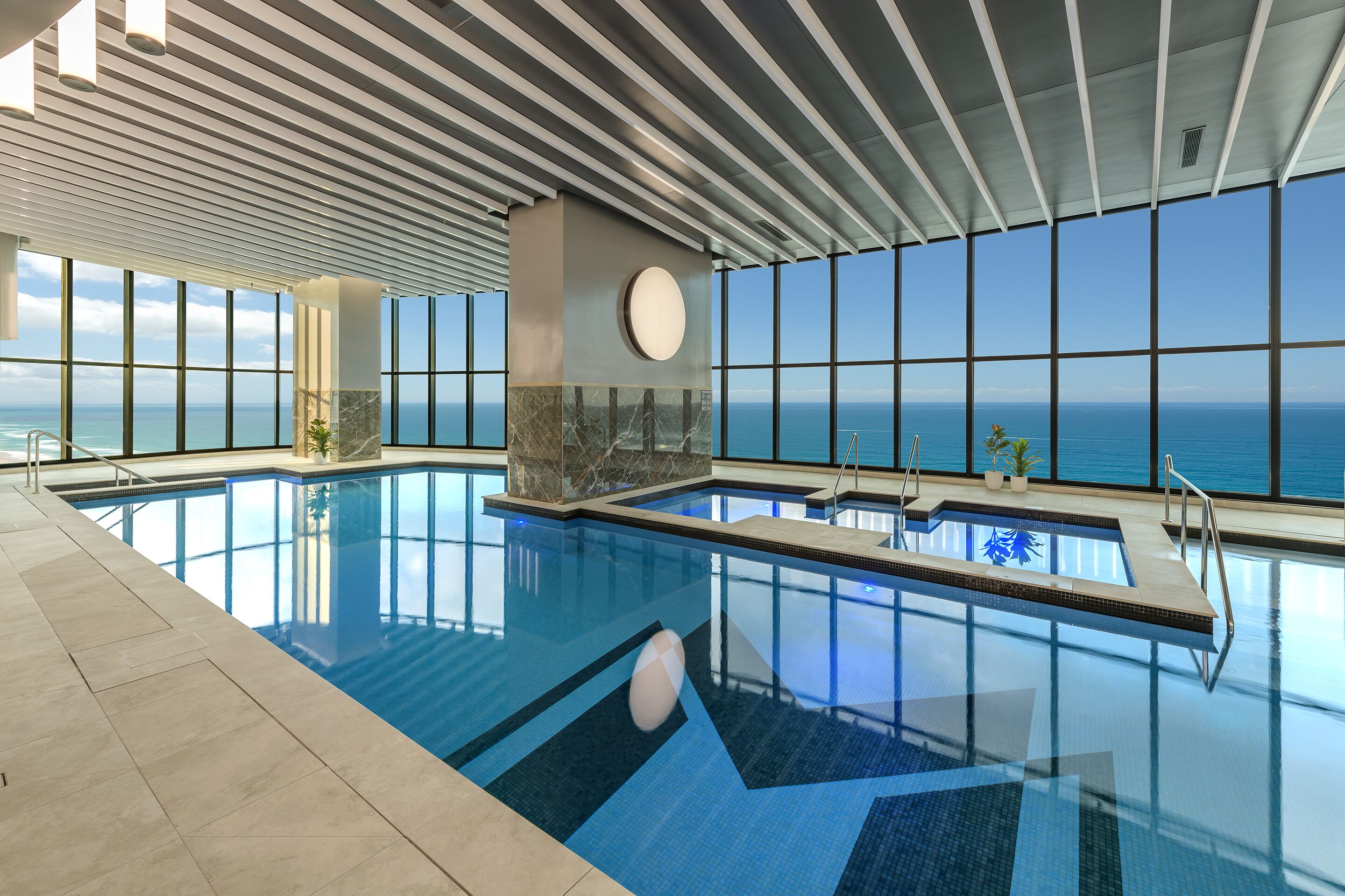 Una piscina interior amb vistes clares a l'oceà a través de grans finestres.