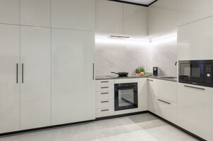 Una cocina moderna con armarios de colores claros, horno empotrado y microondas.
