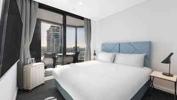 A modern hotel room with a large bed, a desk, and a view of the city.