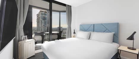 Una habitación de hotel moderna con una cama grande, un escritorio y vistas a la ciudad.