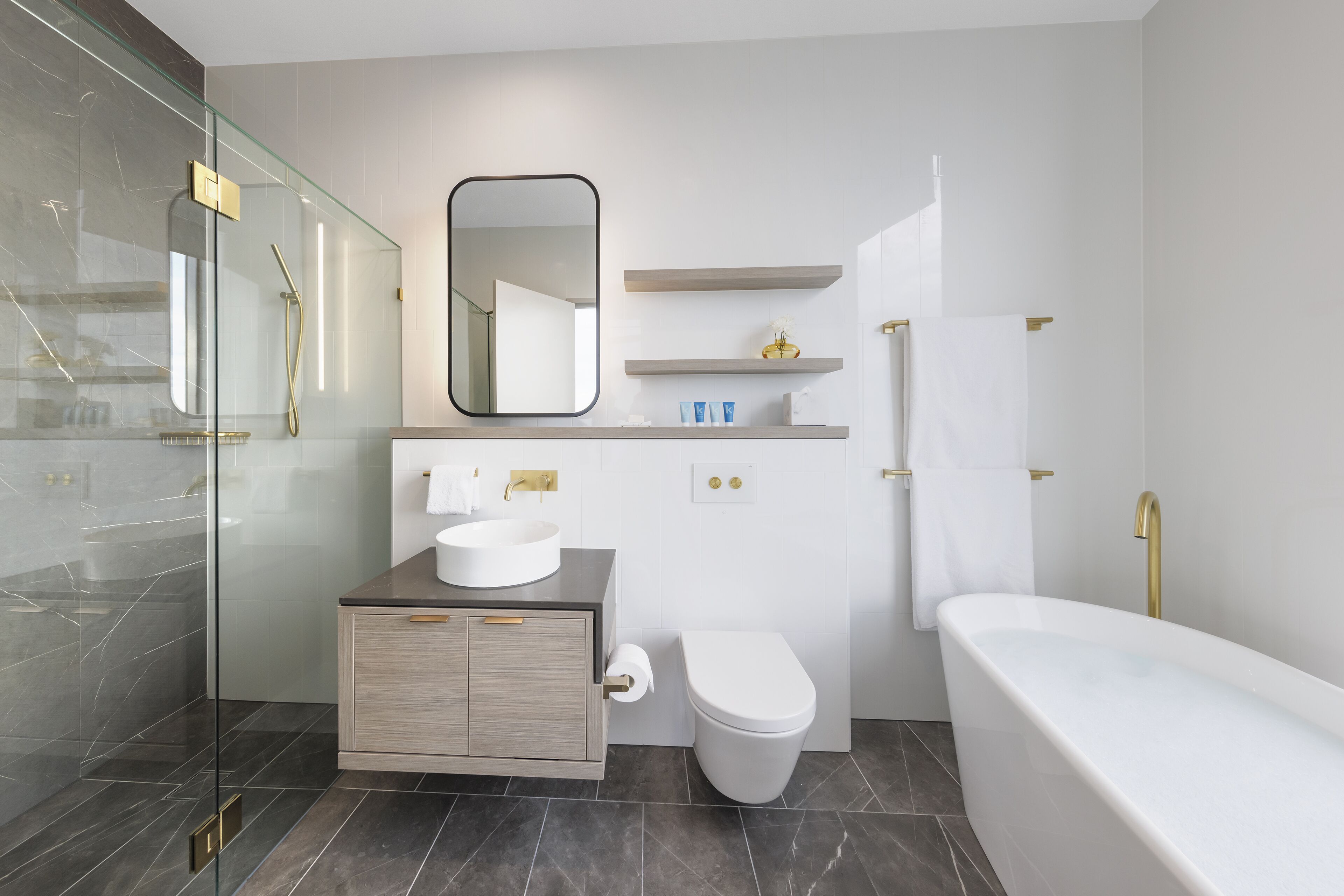 Un baño moderno con ducha de vidrio, lavamanos blanco, inodoro y bañera.