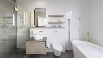 Un baño moderno con ducha de vidrio, lavamanos blanco, inodoro y bañera.