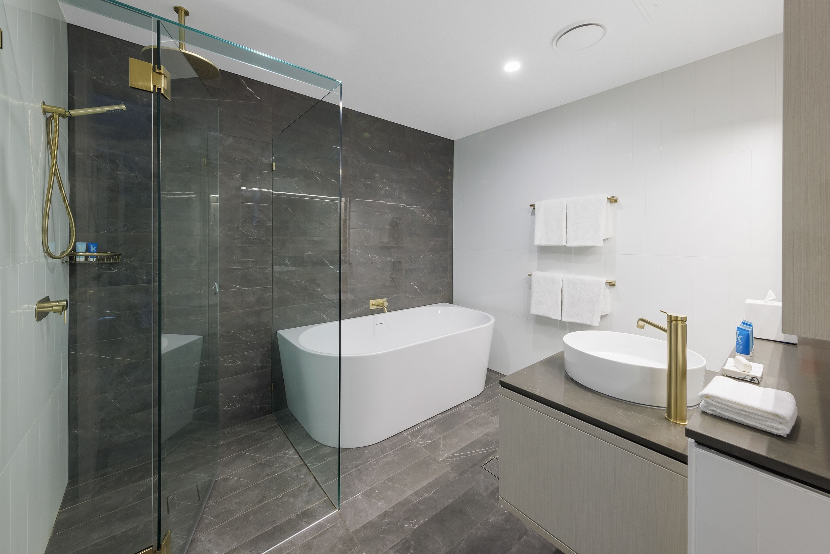 A modern bathroom with a glass-enclosed shower, a freestanding bathtub, and a vanity with a sink and towel rack.