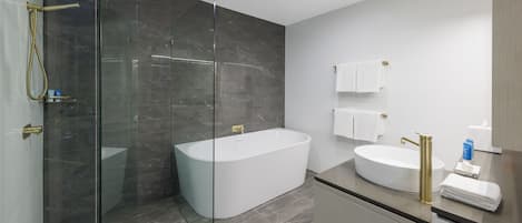 A modern bathroom with a glass-enclosed shower, a freestanding bathtub, and a vanity with a sink and towel rack.